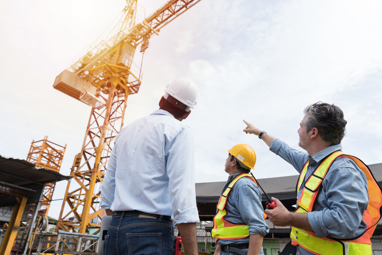 Team of male engineer construction using digital tablet for discussing of structure of building at construction site. Group of male construction builder working at construction site